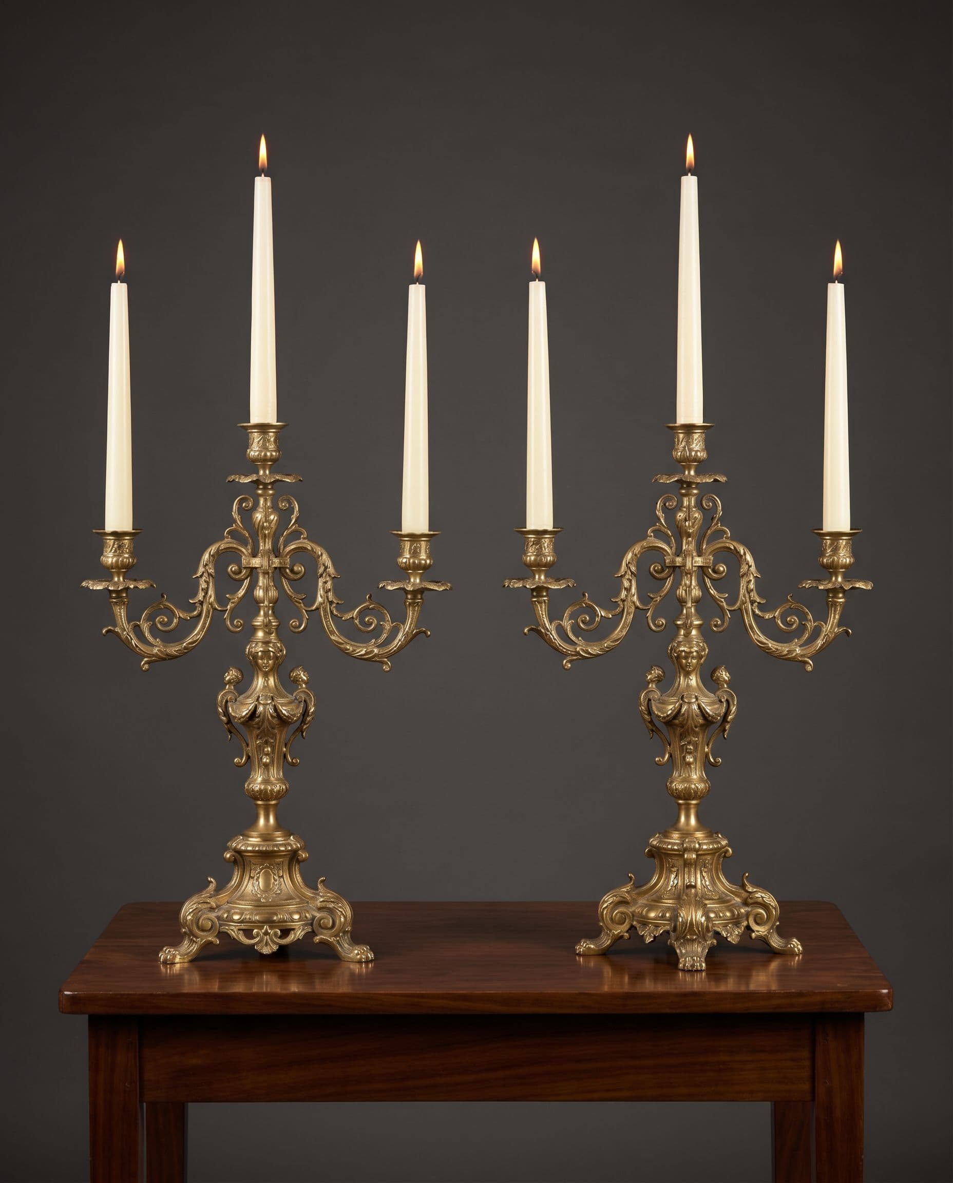 Pair of brass candelabra with ivory tapered candles